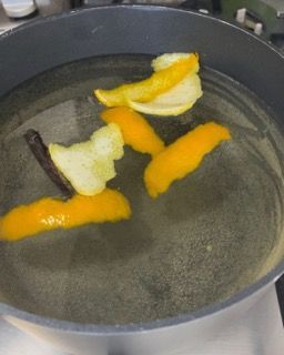 Una pentola d'acqua con dentro delle arance sbucciate