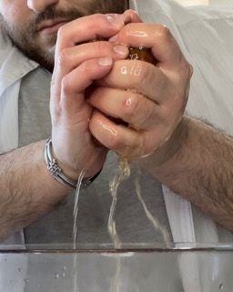 Un uomo tiene in mano un oggetto marrone e da esso esce dell'acqua