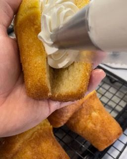 Una persona tiene in mano un pezzo di torta con la panna montata sopra.