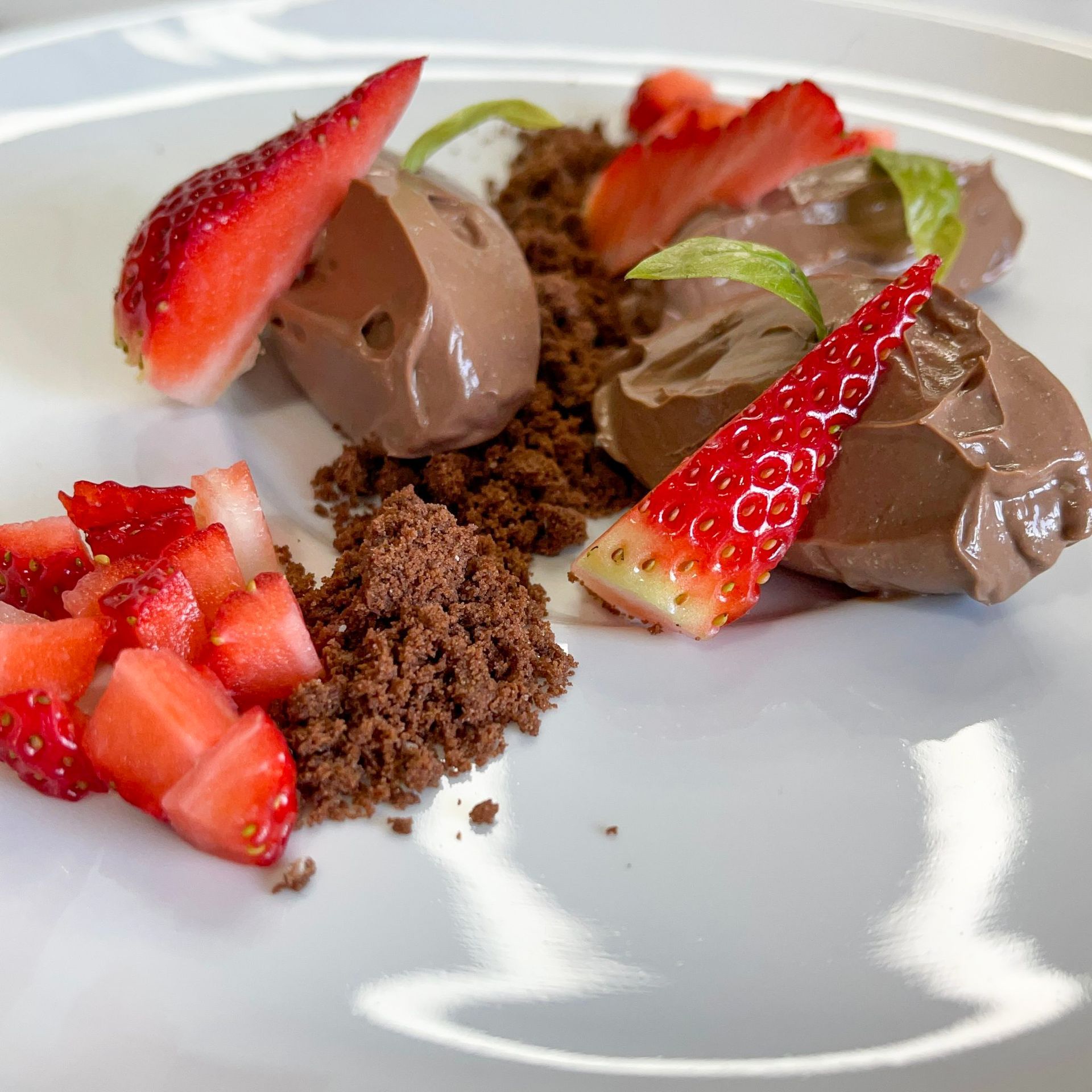 Un piatto bianco con sopra mousse al cioccolato e fragole