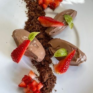 Un piatto bianco con sopra mousse al cioccolato e fragole