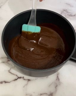 Una ciotola di salsa al cioccolato con una spatola dentro