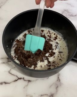 Una persona mescola con una spatola una ciotola di gocce di cioccolato e latte.