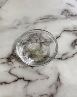 Una piccola ciotola di vetro piena d'acqua è appoggiata su un tavolo di marmo.