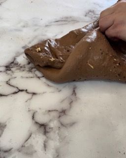 Una persona tiene in mano un pezzo di cioccolato su una superficie di marmo