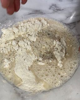 Una persona sta versando la farina in una ciotola piena di liquido.