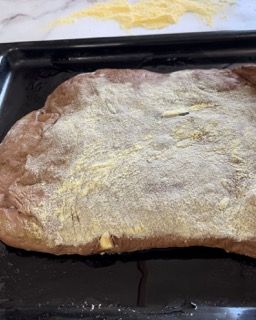Un pezzo di pane è appoggiato su una padella ricoperta di farina.