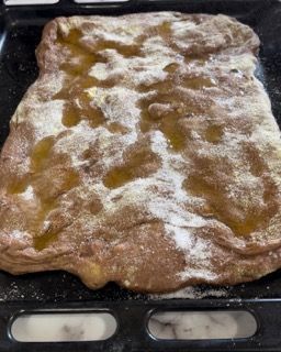 Una pizza è adagiata su un vassoio con olio e zucchero a velo.