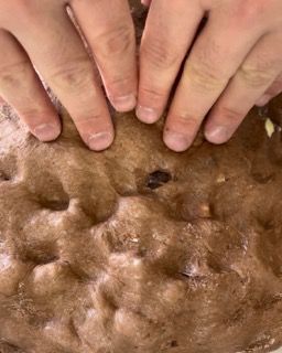 Un primo piano delle mani di una persona su una torta al cioccolato.