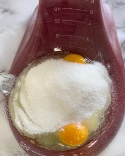 Uova intere e zucchero semolato in una ciotola, pronte per essere montate.