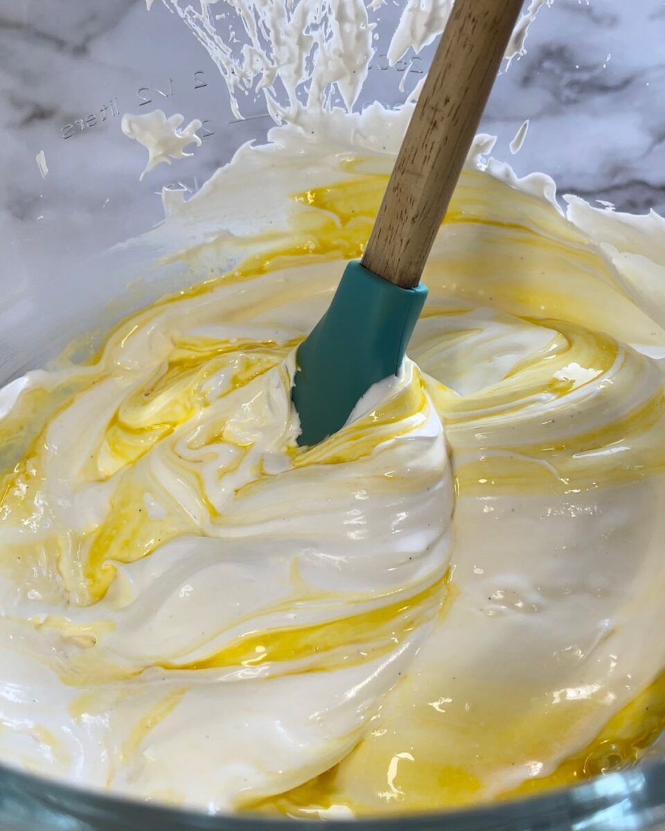 Primo piano di una ciotola di panna montata con una spatola dentro.