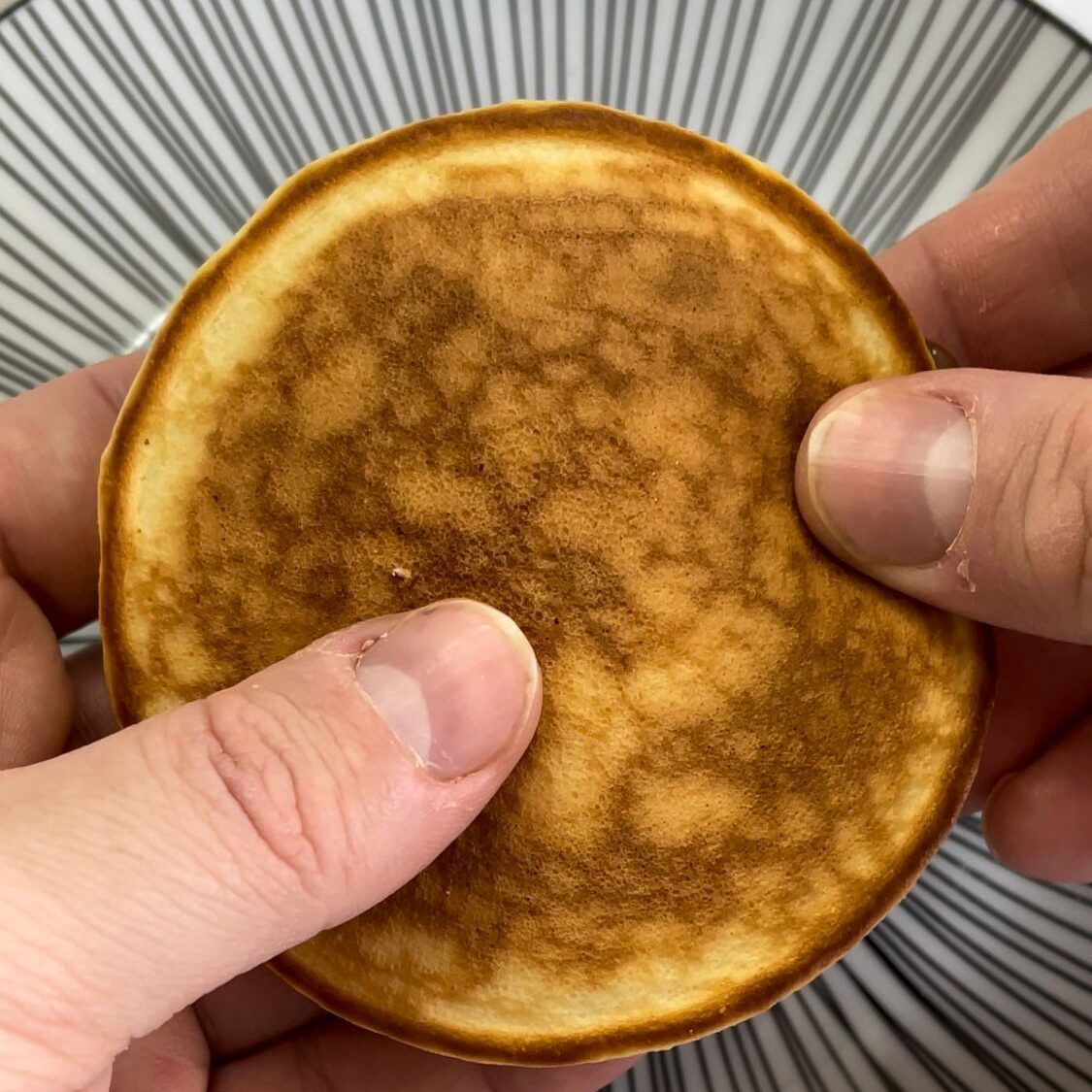 Una persona tiene in mano un pancake con il dito sopra.