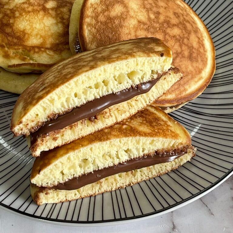 Un primo piano di due pancake con salsa al cioccolato su un piatto.