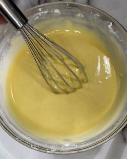 Una frusta è in una ciotola di liquido giallo.