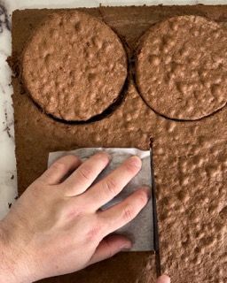 Una persona sta tagliando un pezzo di torta al cioccolato con una spatola