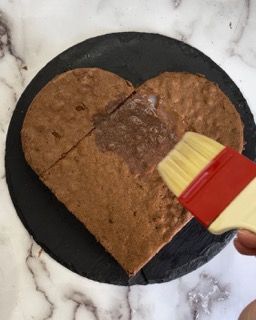 Un biscotto a forma di cuore viene spennellato con salsa al cioccolato
