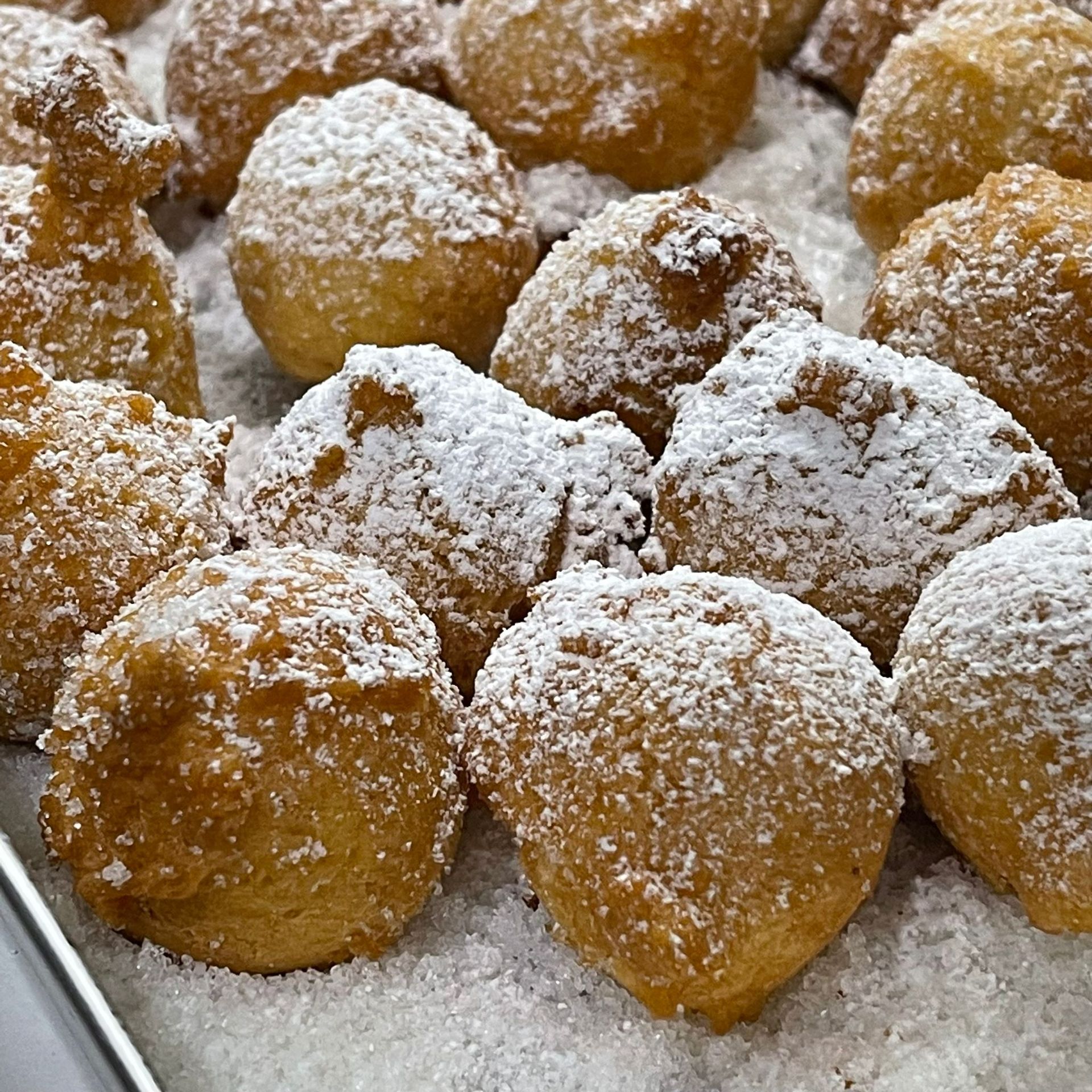 Un mucchio di ciambelle sono ricoperte di zucchero a velo