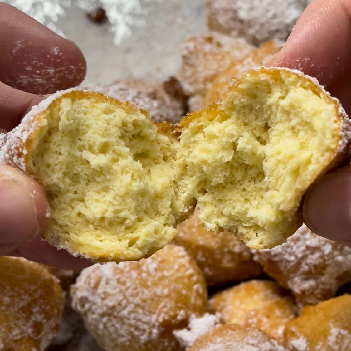 Una persona tiene in mano una ciambella a cui è stato dato un morso.