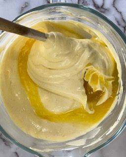 Una ciotola di glassa con un cucchiaio dentro su un tavolo.