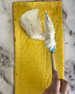 Una persona sta spalmando la panna montata su una fetta di torta gialla.