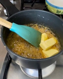 Una padella piena di burro e una spatola sul fornello.