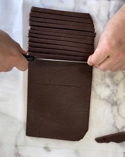 Una persona sta tagliando un pezzo di cioccolato a bastoncini