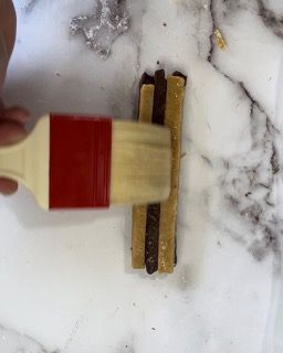 Una persona tiene un pennello sopra un pezzo di cibo.