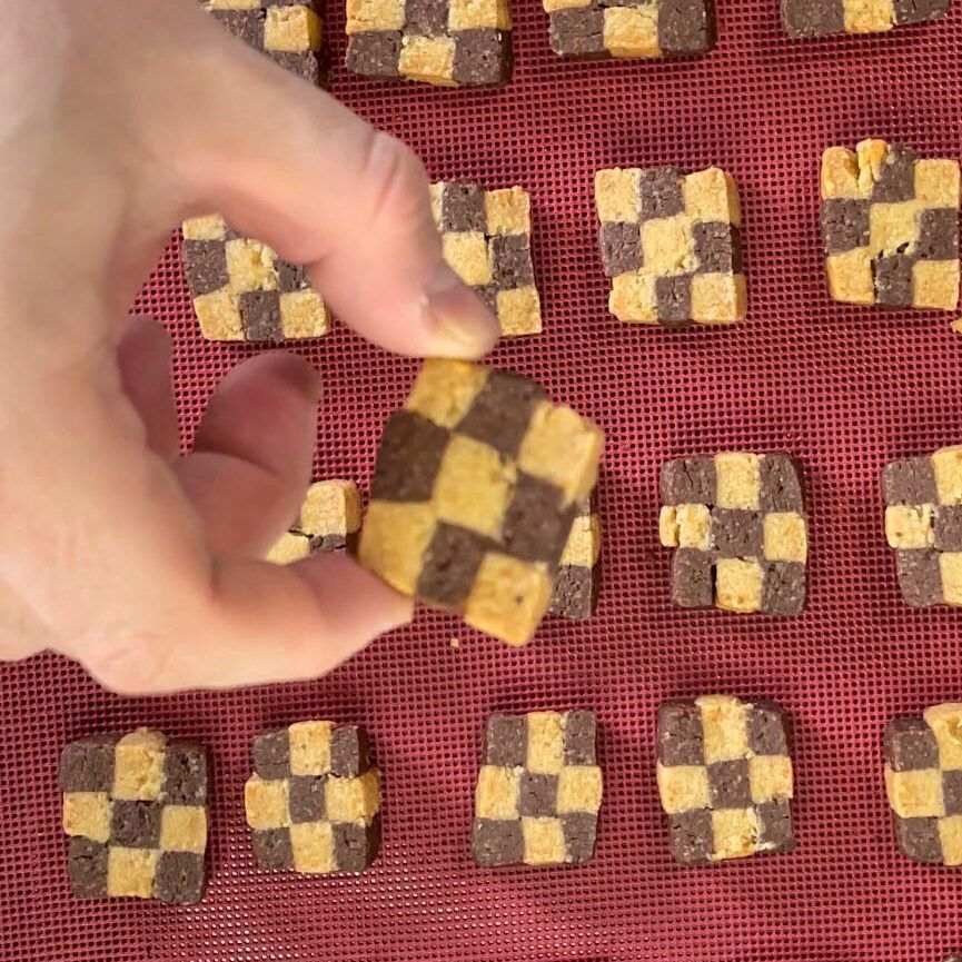 Una persona tiene in mano un biscotto a scacchi.