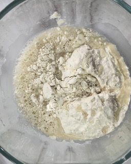 Una ciotola di vetro riempita con un composto di farina e liquido.