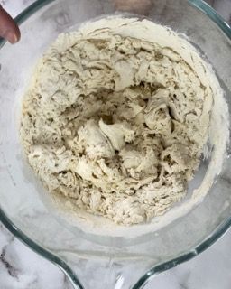 Una persona tiene in mano una ciotola di vetro piena di una sostanza bianca.