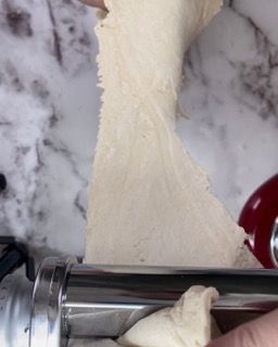 Una persona sta usando una macchina per la pasta per fare l'impasto.