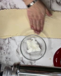 Una persona sta tagliando un pezzo di impasto in una ciotola.