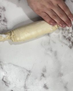 Una persona sta stendendo la pasta con un mattarello su un tavolo.