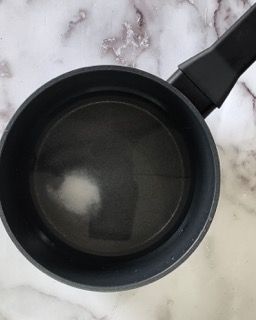 Una pentola nera piena d'acqua è appoggiata su un tavolo.