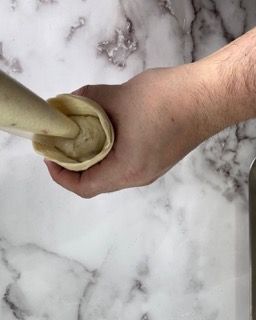 Una persona tiene in mano un pezzo di pasta.