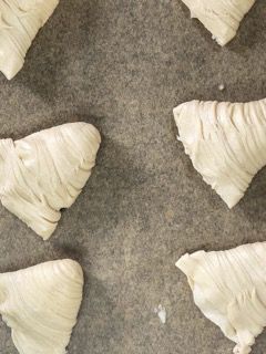 Un mucchio di triangoli di pasta sono appoggiati su un tavolo.