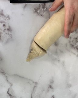 Una persona sta stendendo la pasta con un mattarello su un tavolo.