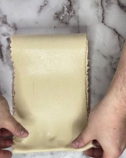 Una persona tiene in mano un pezzo di pasta.