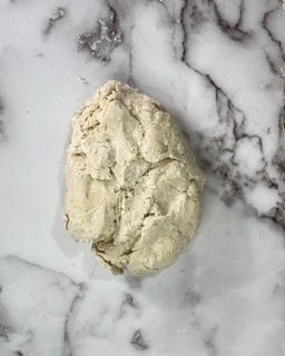 Una palla di pasta è appoggiata su una superficie di marmo.