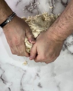 Una persona sta impastando l'impasto su un tavolo di marmo.