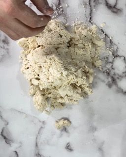 Una persona sta impastando un impasto su una superficie di marmo.