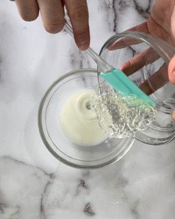 Una persona versa del liquido in una ciotola con un cucchiaio.