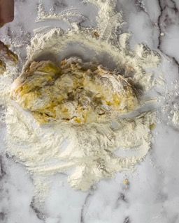 Una persona sta mescolando gli ingredienti in una ciotola su una superficie di marmo.