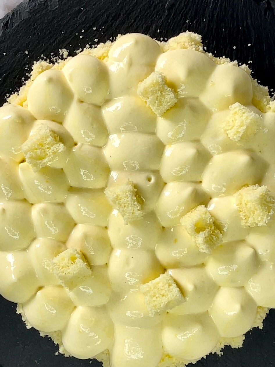 Primo piano di una torta con glassa bianca e marshmallow su un piatto nero.