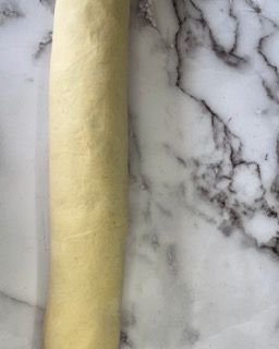 Un rotolo di pasta è appoggiato su un bancone di marmo.