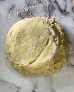 Una palla di pasta è appoggiata su una superficie di marmo.