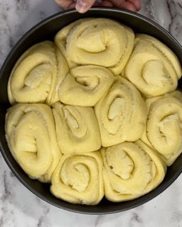 Una persona tiene in mano una padella piena di rotoli di pasta.