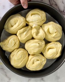 Una persona tiene in mano una padella piena di rotoli di pasta.