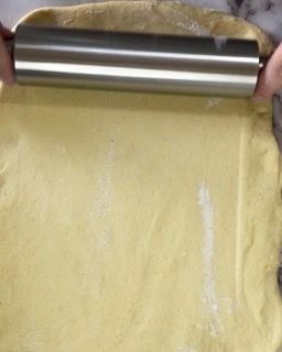 Una persona sta stendendo la pasta con il mattarello.