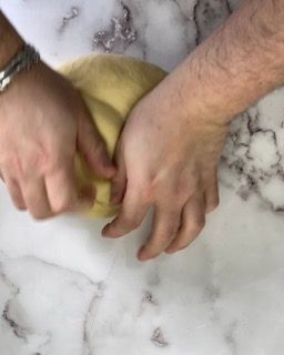 Una persona sta impastando una palla di pasta su un tavolo.